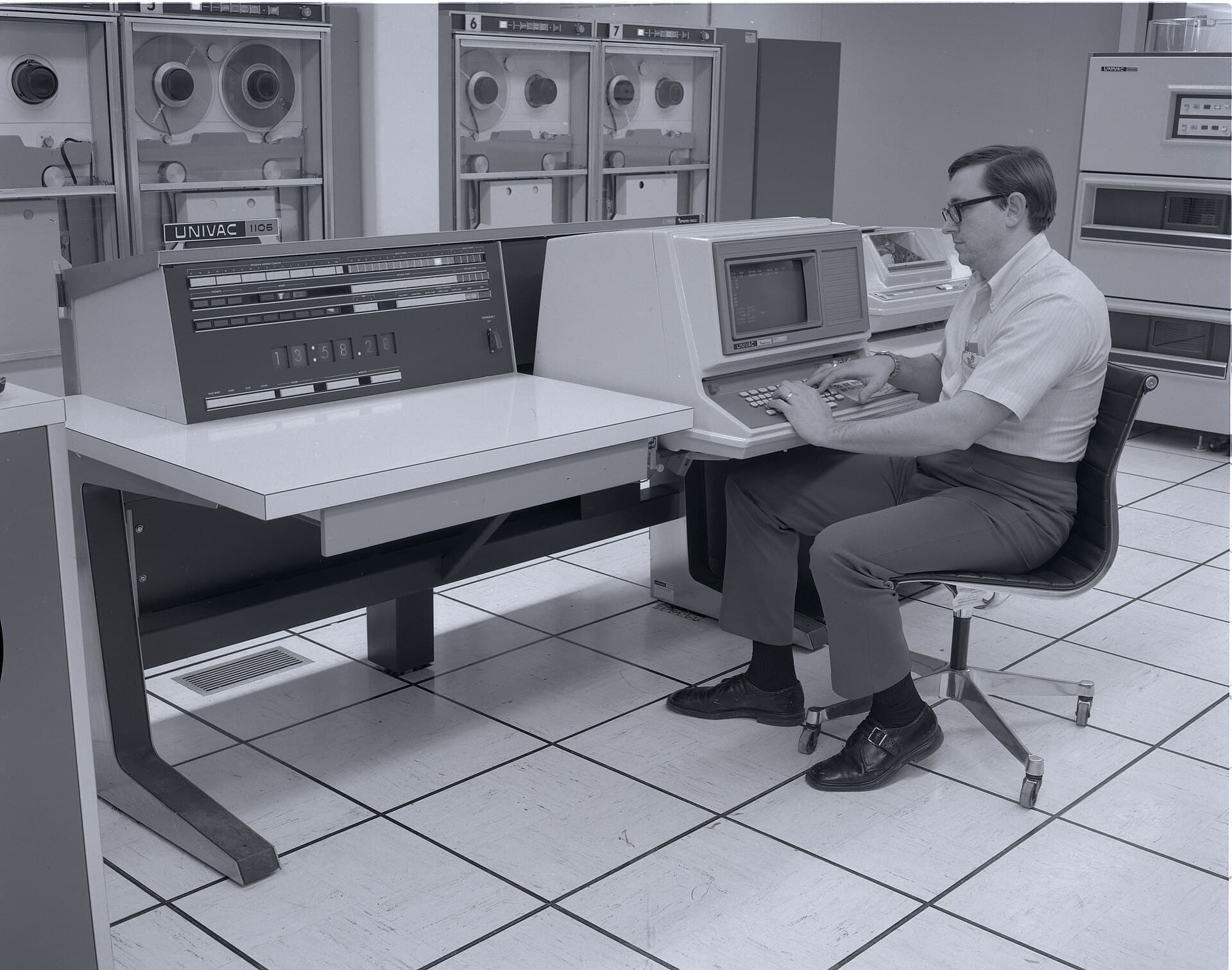 An operator at a console in a large computer room