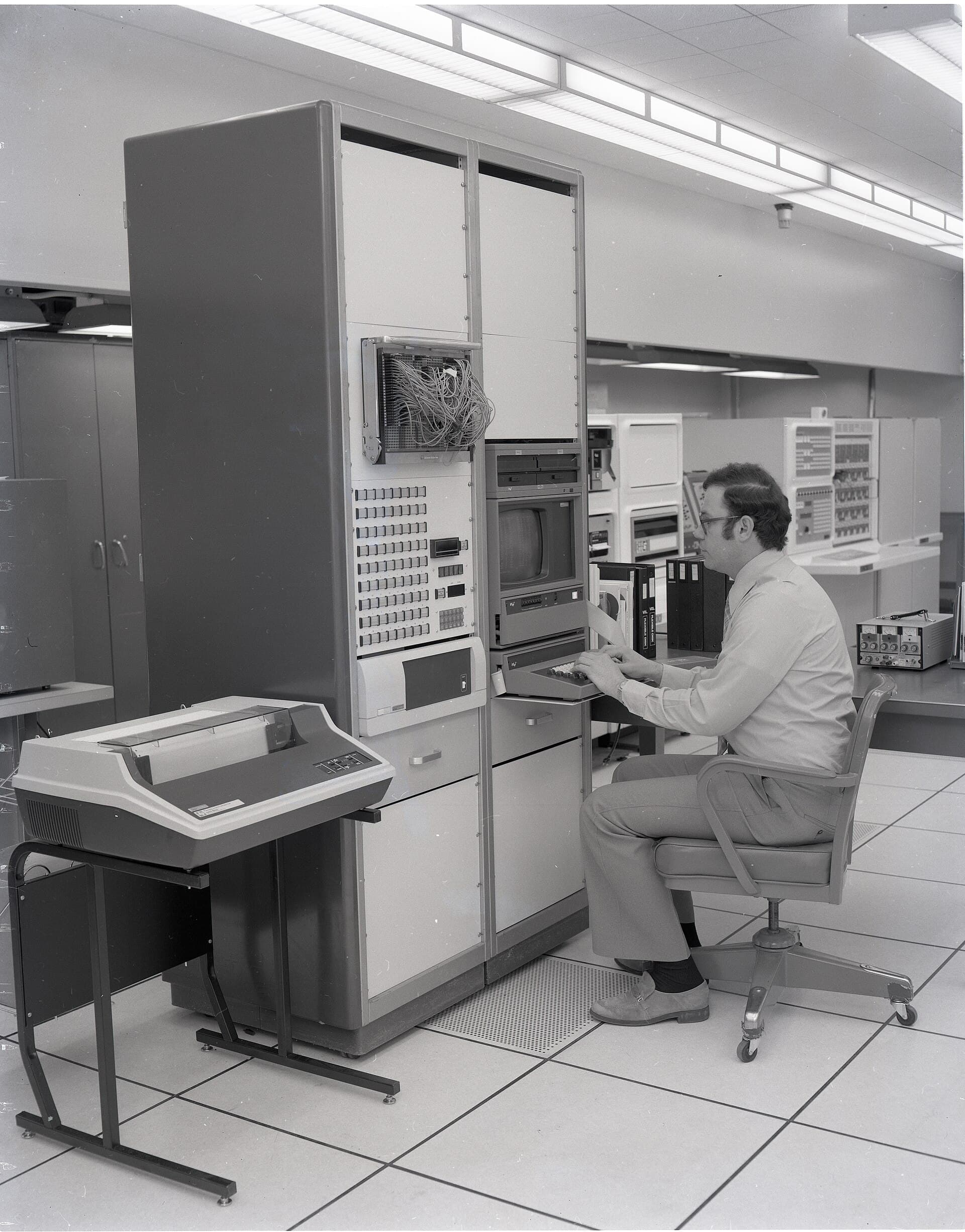 An operator at a terminal beside mainframe cabinets