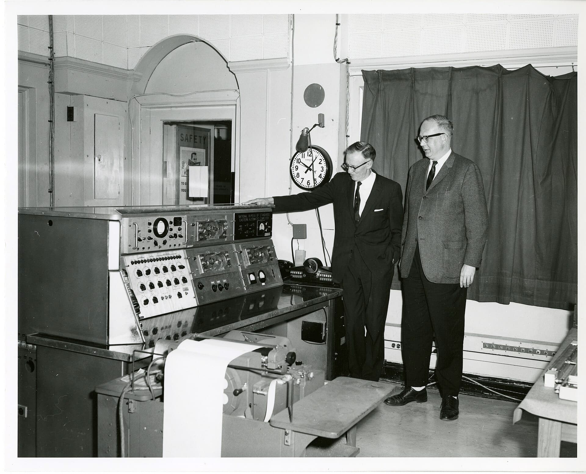 Two men standing at the SEAC control console