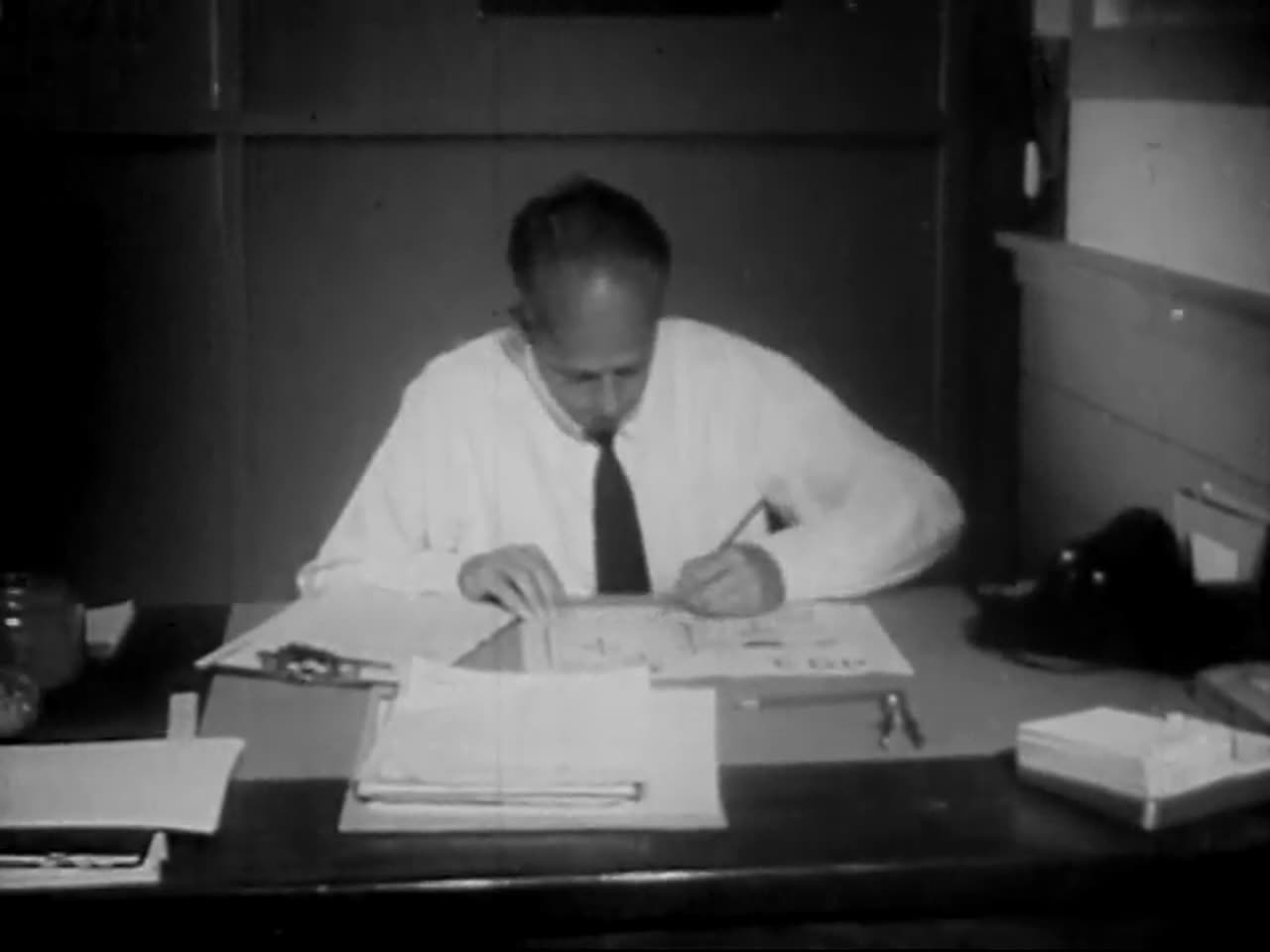 A 1950s office worker writing at a desk