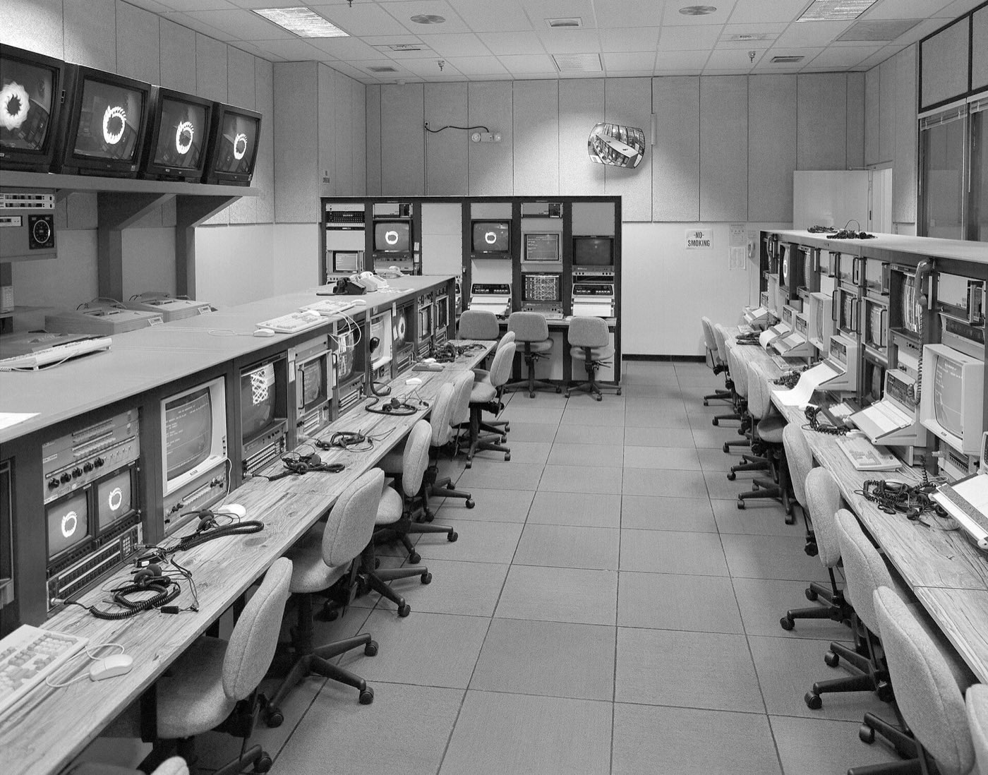 A mission control room with rows of consoles under wall displays